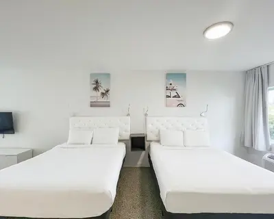 two beds in a room with white walls at Tranquilo in Fort Lauderdale