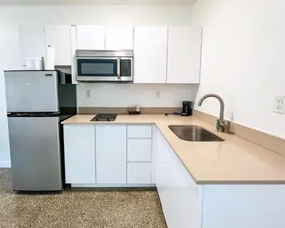 a kitchen with white cabinets and a stainless steel refrigerator at Tranquilo in Fort Lauderdale