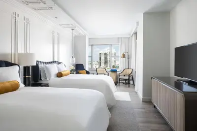 a hotel room with two beds and a television at The Ritz-Carlton, South Beach in Miami Beach
