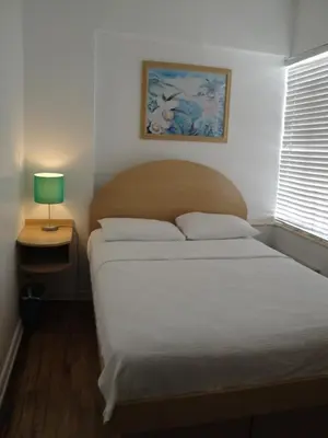 a bedroom with a bed and a lamp on a table at Island House South Beach in Miami Beach
