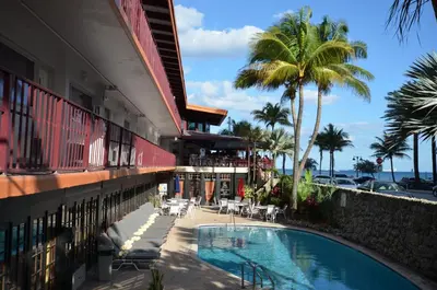 a swimming pool next to a building with palm trees at Sea Club Ocean Resort in Fort Lauderdale