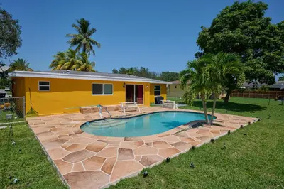 a swimming pool in a yard with a yellow house at Fabulous Hollywood Living Space in Hollywood