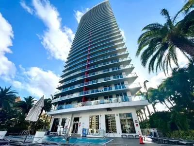 a tall building with a pool in front of it at Beachwalk Resort Hallandale Ocean and Canal View Apartments 5 Min from the Beach in Hallandale Beach