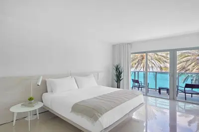 a white bedroom with a bed and a view of the ocean at Beach Haus Bal Harbour in Miami Beach