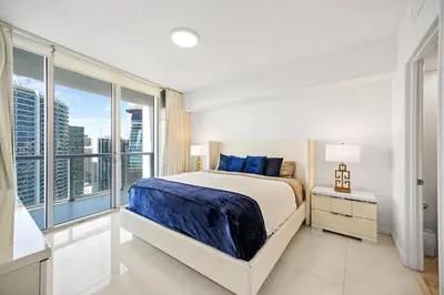 a white bedroom with a bed and a large window at Majestic High Rise Unit with Ocean view in Miami