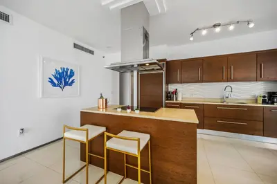 a kitchen with wooden cabinets and a counter with stools at Breathtaking Ocean View Unit Icon Brickell W in Miami