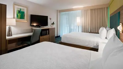 a hotel room with two beds and a desk and a television at Best Western Plus Oceanside Inn in Fort Lauderdale