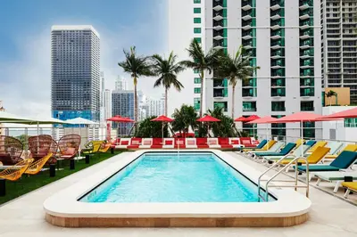 a pool on the roof of a building with chairs and umbrellas at citizenM Miami World Center in Miami
