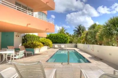 a swimming pool with chairs and a table next to a building at Dream Destinations at Ocean Place in Miami Beach
