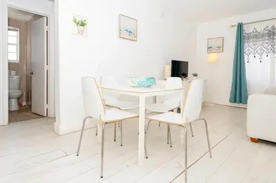 a white dining room with a white table and chairs at South of Fifth Ocean Drive Apt in Miami Beach