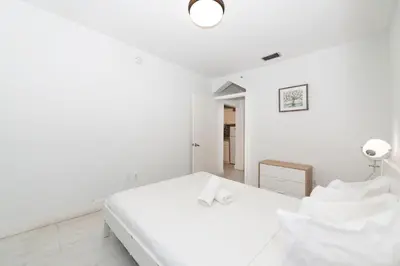 a white bedroom with a bed and a lamp at South of Fifth Ocean Drive Apt in Miami Beach