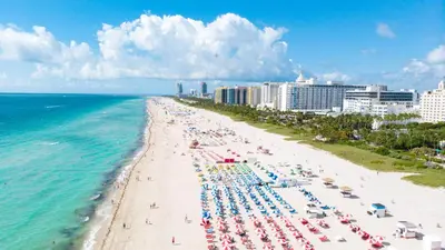 a beach with chairs and umbrellas and the ocean at South of Fifth Ocean Drive Apt in Miami Beach