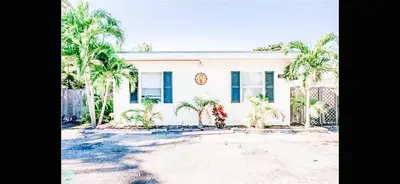 a white house with palm trees in front of it at Lovely Bohemian Apartment in Fort Lauderdale
