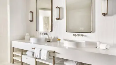 a white bathroom with two sinks and two mirrors at Four Seasons Hotel and Residences Fort Lauderdale in Fort Lauderdale