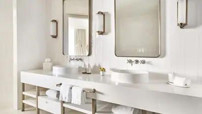 a white bathroom with two sinks and two mirrors at Four Seasons Hotel and Residences Fort Lauderdale in Fort Lauderdale