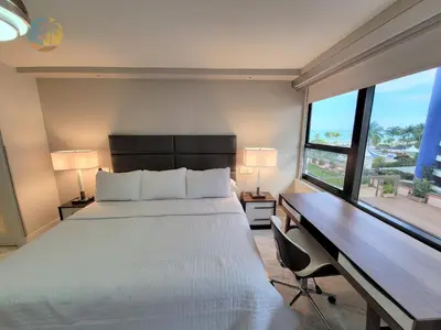 a bedroom with a bed and a desk with two lamps at Deluxe Beach Resort - HORA RENTALS in Miami Beach