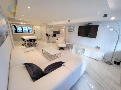 a living room with a white couch and a tv at Deluxe Beach Resort - HORA RENTALS in Miami Beach