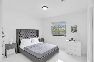 a white bedroom with a bed and a window at Renzzi Wynwood Apartments in Miami