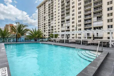 a large pool with tables and umbrellas next to buildings at Cambria Hotel Fort Lauderdale Beach in Fort Lauderdale