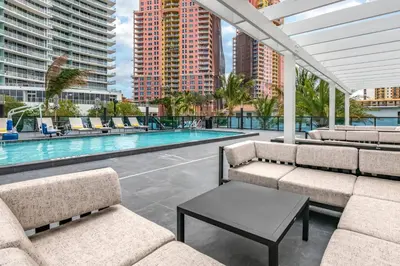 a patio with chairs and a pool with buildings at Cambria Hotel Fort Lauderdale Beach in Fort Lauderdale