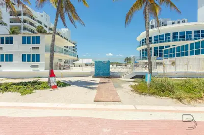 a beach with two palm trees and a building at Girasole Rentals Suites in Miami Beach
