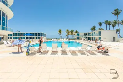 a group of people sitting in chairs by a swimming pool at Girasole Rentals Suites in Miami Beach