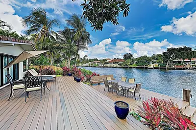 a wooden deck with chairs and tables and a river at Middle River Lookout in Fort Lauderdale