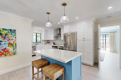 a kitchen with white cabinets and a blue island at Middle River Lookout in Fort Lauderdale