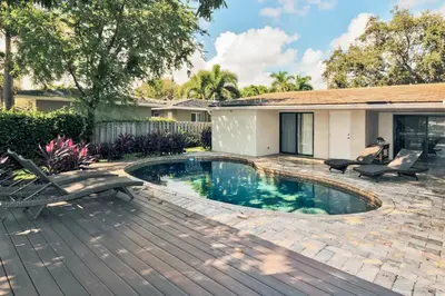 a swimming pool with two chairs and a house at Middle River Lookout in Fort Lauderdale