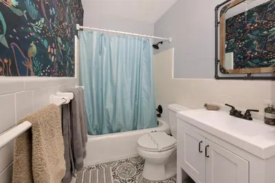 a bathroom with a blue shower curtain and a toilet at Cozy Cottage Near Beach in Hollywood