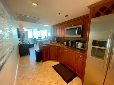 a kitchen with wooden cabinets and a white refrigerator at Large luxurious direct ocean front Penthouse or Deluxe 1 BR ocean front condo-Beach access- Free parking- Remodeled in Miami Beach