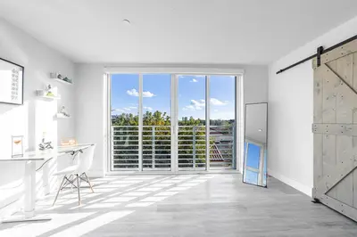 a white kitchen with a desk and a sliding glass door at Lofts of Aventura in Miami