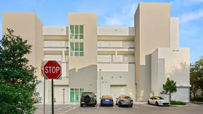 a stop sign in front of a building with parked cars at Lofts of Aventura in Miami