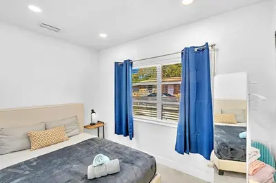 a bedroom with a bed and a window with blue curtains at Boutique One Bdrm Close To Aventura Mall & Beach in Hallandale Beach