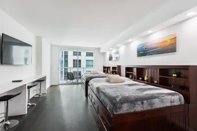 a bedroom with two beds and a desk and a tv at Studios in Brickell with Pool, Gym, free parking and Game Room in Miami