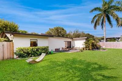 a house with a yard with chairs and a palm tree at Mid-Century Modern Oasis in Miami