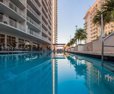 a swimming pool in a hotel with palm trees and buildings at 1Bd Apt with Free Parking and Amazing View in Miami