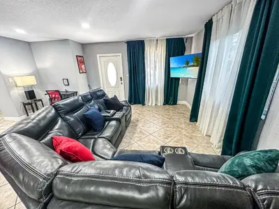 a living room with a leather couch and a television at Escape GameRoom, BAR, BBQ, Spacious,KING Bed, All Luxury mattresses, Near Beach, 6 blocks away from Bars, Nite Clubs, Res, Shops in Miami