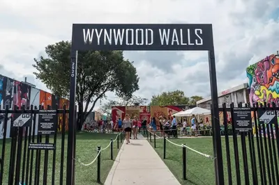 a street sign for wynwood walls in a park at Escape GameRoom, BAR, BBQ, Spacious,KING Bed, All Luxury mattresses, Near Beach, 6 blocks away from Bars, Nite Clubs, Res, Shops in Miami