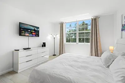 a white bedroom with a white bed and a tv at Yacht Club Miami Suite 2 Bedroom and 2 Bathroom With Baby Crib & Free Parking in Miami