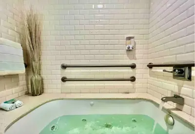 a bath tub in a bathroom with white tiles at The Carlyle Oceanfront Luxe Condo Miami Beach in Miami Beach