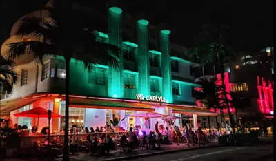 a group of people standing outside of a building at night at The Carlyle Oceanfront Luxe Condo Miami Beach in Miami Beach