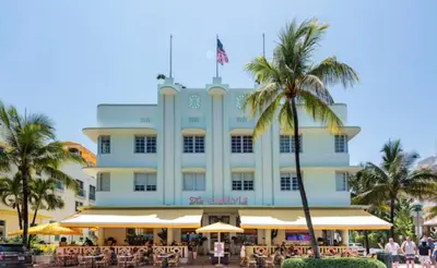 a large building with palm trees in front of it at The Carlyle Oceanfront Luxe Condo Miami Beach in Miami Beach