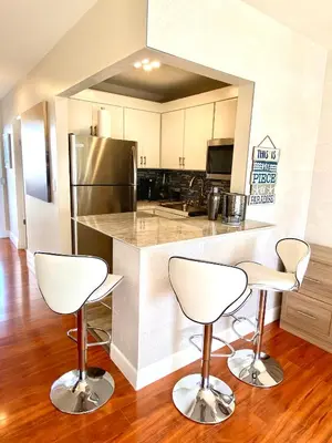 a kitchen with two bar stools in front of a counter at Modern waterfront apartment with Miami Skyline view, free parking 5 mins drive to Miami Beach in Miami Beach