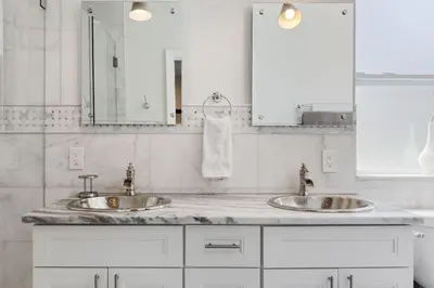 a white bathroom with two sinks and a mirror at Las Olas Villa with HEATED Salt Water Pool in Fort Lauderdale