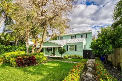 a green house with a fence and a yard at Las Olas Villa with HEATED Salt Water Pool in Fort Lauderdale