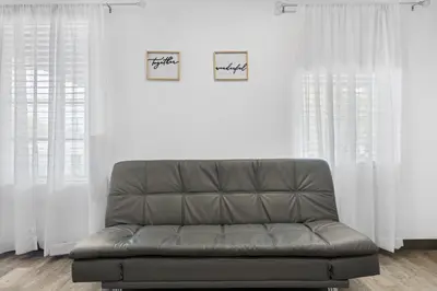a couch in a living room with white curtains at Sunset Inn-South Miami in South Miami