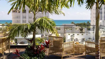 a patio with chairs and palm trees and the ocean at Uma House by Yurbban South Beach in Miami Beach