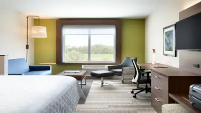 a hotel room with a bed and a desk and chairs at Holiday Inn Express & Suites - Miramar by IHG in Miramar