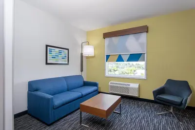 a living room with a blue couch and a chair at Holiday Inn Express & Suites - Miramar by IHG in Miramar